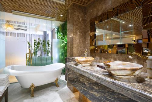 a bathroom with a tub and two sinks on a counter at Winsuites Saigon Hotel in Ho Chi Minh City