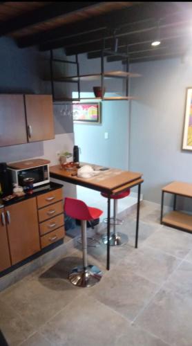 a kitchen with a wooden table and a red stool at Coqueto departamento in Villa Elisa