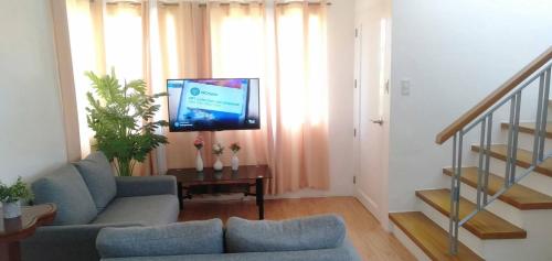 a living room with a couch and a flat screen tv at Avida 3-Bedroom Vacation House with Pool in Minuluang
