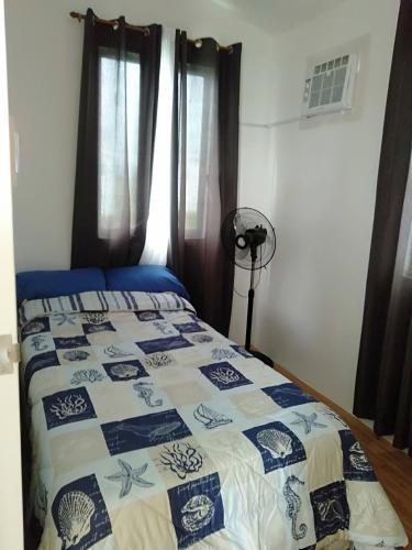 a bedroom with a bed with a blue and white quilt at Avida 3-Bedroom Vacation House with Pool in Minuluang