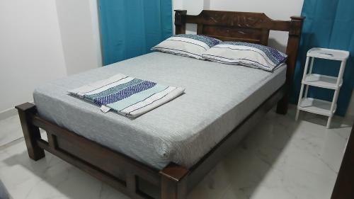 ein Bett mit einem Holzrahmen mit zwei Kissen darauf in der Unterkunft Hospedaje MangleRojo - Cerca al Mar in Coveñas