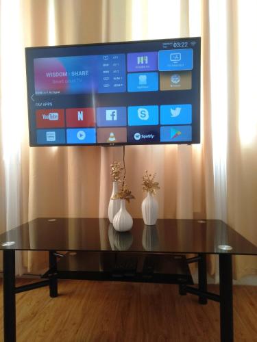 a tv on a wall with two vases on a table at Avida 3-Bedroom Vacation House with Pool in Minuluang