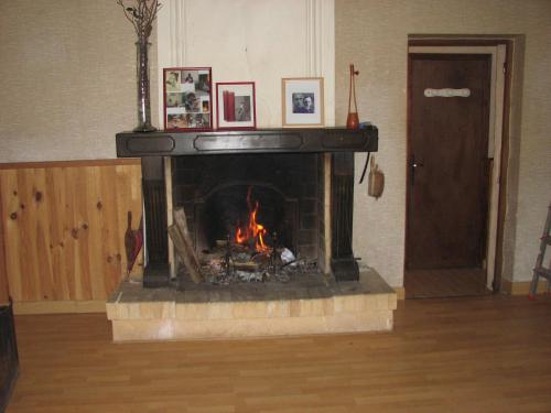 a fireplace in a living room with a fire in it at Duplex Carreyrou in Beaumont-du-Périgord