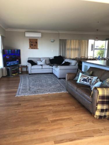 a living room with two couches and a television at Coppelia Sunrise in Omokoroa