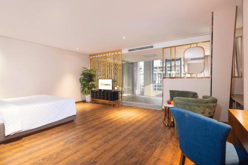 a bedroom with a bed and a living room at Winsuites Saigon Hotel in Ho Chi Minh City