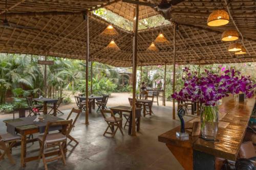 a restaurant with tables and chairs and a vase of purple flowers at Palm Forest Palolem in Palolem