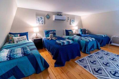 three beds in a room with blue and white sheets at Charming Waterfront Cabin - Sleeps 10 in Rocky Mount