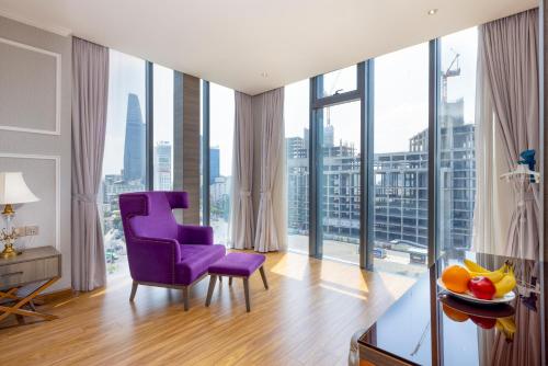 a living room with a purple chair and large windows at Winsuites Saigon Hotel in Ho Chi Minh City