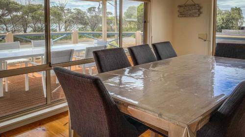 a dining room with a table and chairs and a balcony at Catch of the Bay in Coffin Bay