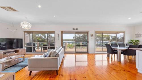 a living room with a white couch and a dining room at Catch of the Bay in Coffin Bay