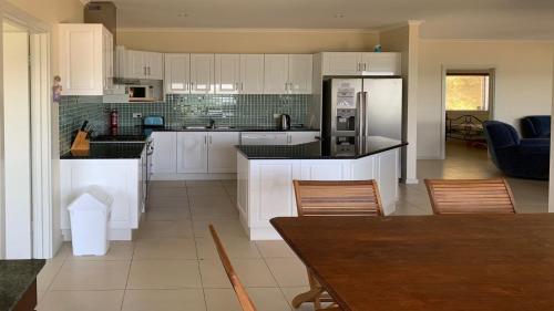 a kitchen with white cabinets and a table and chairs at The Beach House - Spectacular Location - Privacy - Right On The Beach in Coffin Bay