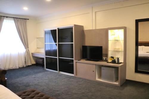 a hotel room with a television and a bedroom at Hotel Felda Residence Tekam , PPP Tun Razak in Kampong Sungai Batu