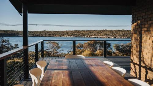 a wooden table and chairs on a balcony with a view of the water at Dusk Coffin Bay in Coffin Bay