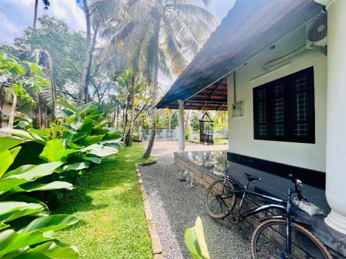 a bike parked next to a building with palm trees at Riverrootsstays in Munroe Island