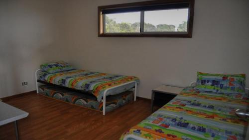 a small room with two beds and a window at Rest A Shore Coffin Bay in Coffin Bay