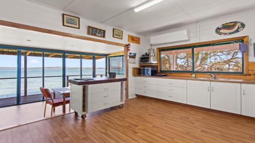 a kitchen with white cabinets and a table and some windows at Kellidie Bliss Is Coffin Bay's Touch Of Paradise - Perfect Couples Retreat in Coffin Bay