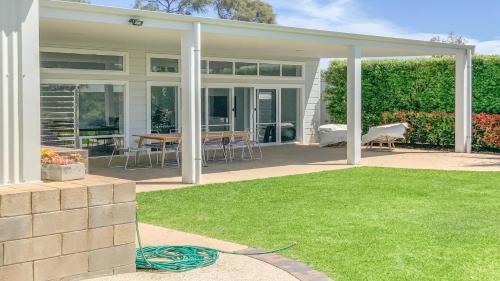 eine Terrasse mit einem Tisch und Stühlen auf einem Rasen in der Unterkunft Shack 207 in Coffin Bay