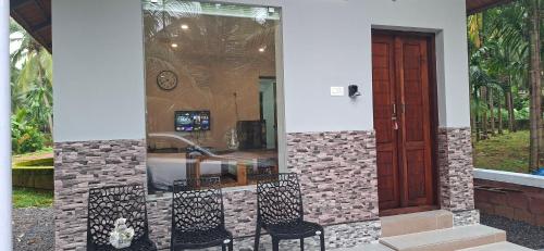 two chairs in front of a house with a door at Bekal Village Homestay in Kāsaragod