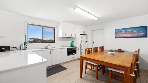 a kitchen with a wooden table and a dining room at Endymion Is Ideally Situated On The Esplanade in Coffin Bay