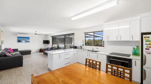 a kitchen with white cabinets and a living room at Endymion Is Ideally Situated On The Esplanade in Coffin Bay