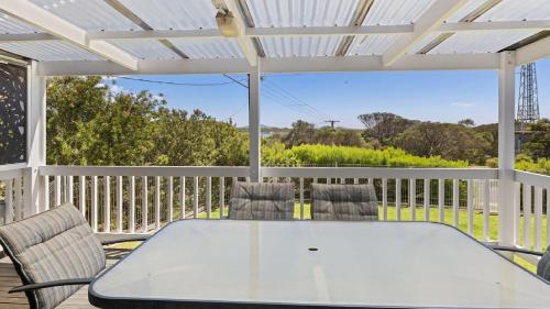 a white table and chairs on a deck with a view at Endymion Is Ideally Situated On The Esplanade in Coffin Bay