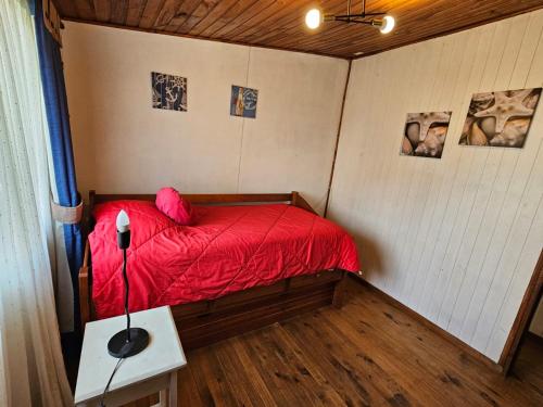 a small bed in a room with a red comforter at Casas Pamelas in Algarrobo