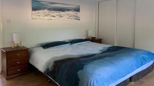 a bedroom with a large bed with two night stands and a painting at Angasi Is One Of Coffin Bay's Premium Properties - With Free Wifi in Coffin Bay