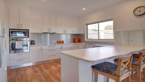 a kitchen with white cabinets and a counter and a clock at Grey On The Bay in Coffin Bay