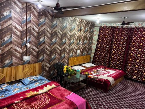 a bedroom with two beds and a table with flowers on it at Aziz Guest House in Srinagar