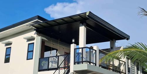 a house with a black roof and a balcony at M11 Z Guest House in Pasuquin