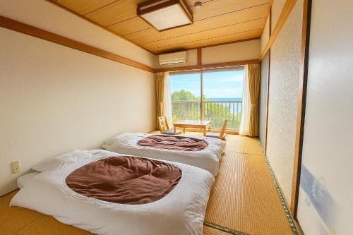 two beds in a room with a large window at 123MUSIC(イズサンミュージック) in Atami