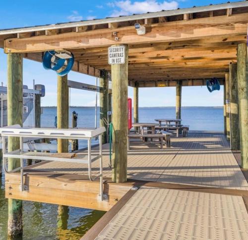 a wooden pier with benches and tables on the water at Bayview Condo, Boat Slip & Launch, Pool & Arcade! The Wild Wahoo! in Orange Beach