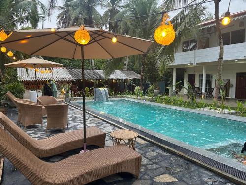 a resort swimming pool with chairs and an umbrella at Inn Sea Horizon Ahungalla in Ahungalla
