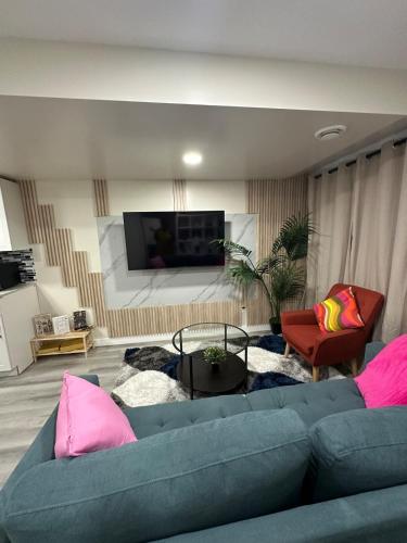 a living room with a blue couch and pink pillows at Elegant & Stylish Basement Suite- Private Entrance in Winnipeg