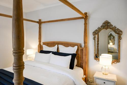 1 dormitorio con cama con dosel y espejo en Carisbrook Cottage, en Armidale