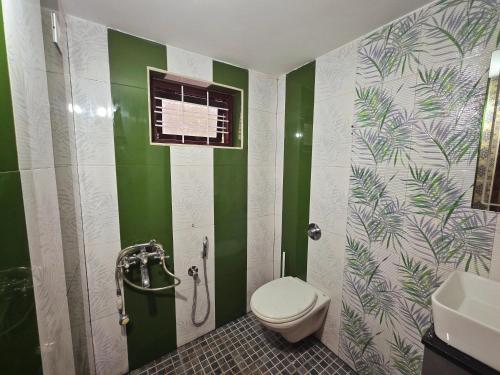 a bathroom with a toilet and green and white walls at Tranquil Nest Villa - 4BHK Villa - Entire Villa stay in Wayanad in Kalpetta