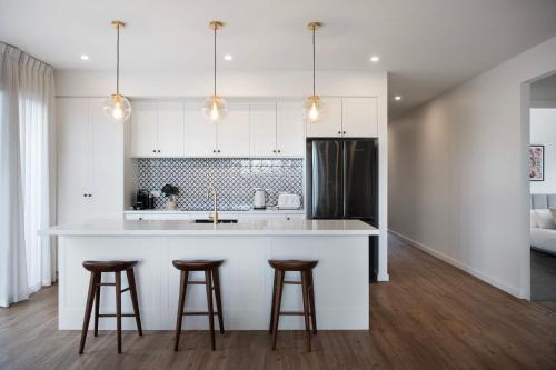 a kitchen with white cabinets and bar stools at Bluestone Haus - stylish home in Daylesford
