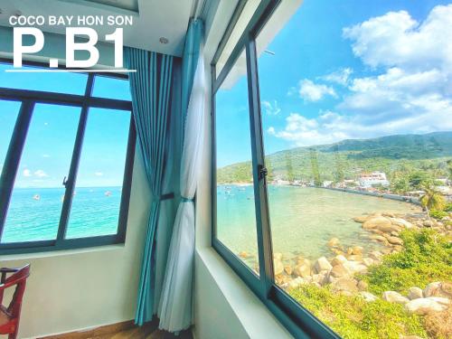 a room with a window looking out at a beach at Coco Bay Hon Son in Lai Sơn