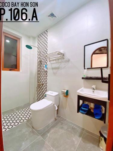 a bathroom with a white toilet and a sink at Coco Bay Hon Son in Lai Sơn