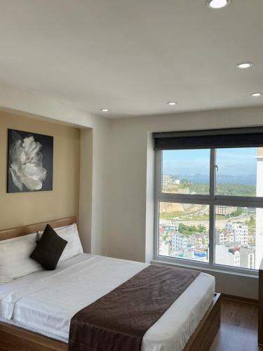 a bedroom with a large bed with a large window at Homestay Ha Long Vip in Ha Long