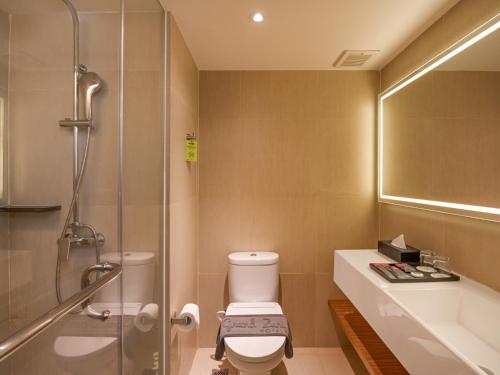 a bathroom with a toilet and a sink and a shower at Grand Zuri Pekanbaru in Pekanbaru