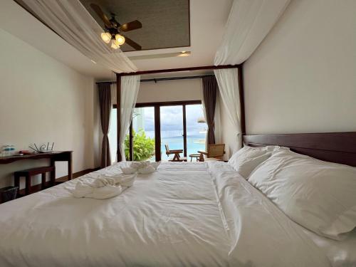 a bedroom with a large white bed with a window at Resort Deja Vu in Siquijor