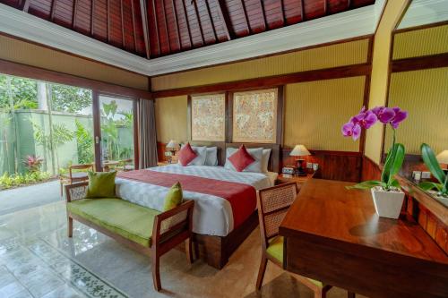 a bedroom with a bed and a table and a desk at Arkamara Dijiwa Ubud in Ubud