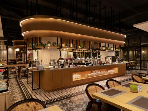 a restaurant with a counter with tables and chairs at Grand Zuri Pekanbaru in Pekanbaru
