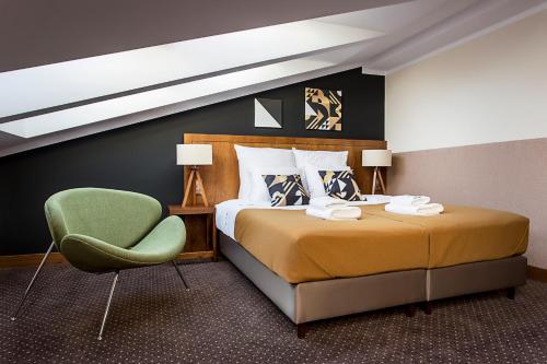 1 dormitorio con 1 cama y 1 silla verde en Zulian Aparthotel by Artery Hotels, en Cracovia