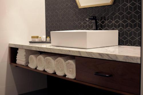 a bathroom with a sink and a bunch of towels at Ellen Hotel in Port Pirie