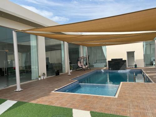 a swimming pool with an umbrella on a house at AlNouf Chalet in Barka