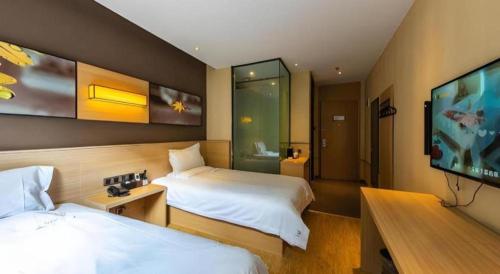 a hotel room with two beds and a flat screen tv at IU Hotel Kunming Jinma Bijifang Joy City in Kunming
