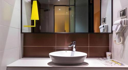 a bathroom with a sink and a mirror at IU Hotel Kunming Jinma Bijifang Joy City in Kunming