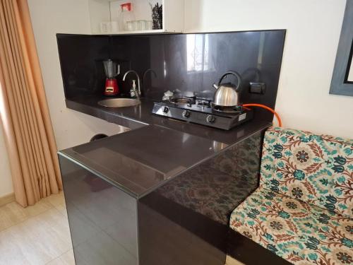 a kitchen with a counter with a stove and a chair at Montemar Apart Hotel - Playa Huanchaco in Huanchaco